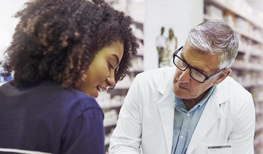 Pharmacist giving a customer prescription meds over the counter